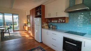 a kitchen with white cabinets and a blue tile wall at Chiton Cottage by the Sea - Restaurants, Bikes, Pets in Hayborough
