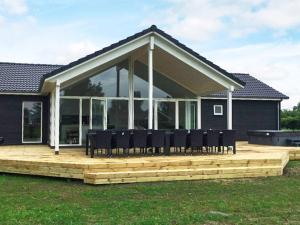 a large deck with black chairs on top of a house at 14 person holiday home in Væggerløse in Marielyst