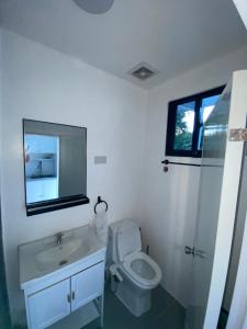 a bathroom with a toilet and a sink and a mirror at JNJ Apartelle in Tacurong +10 photos