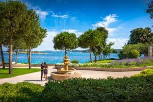 dos personas de pie junto a una fuente en un parque en Maistra Select Island Hotel Istra, en Rovinj