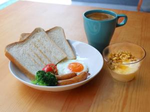 a plate of breakfast food with eggs sausage broccoli and toast at Imano Tokyo Hostel in Tokyo