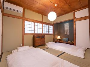 2 letti in una camera con 2 finestre di 高松市の築45年のお家をリノベーションした民泊古都 a Takamatsu