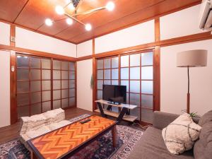 un soggiorno con un divano e una TV di 高松市の築45年のお家をリノベーションした民泊古都 a Takamatsu