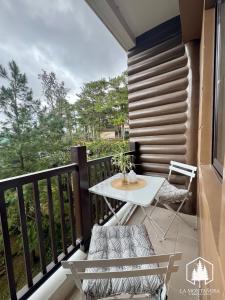 a balcony with a white table and chairs on it at Solace - 1BR Brenthill Condo with Balcony Near Session and SM in Baguio