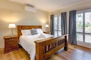 1 dormitorio con cama de madera y ventana grande en Driftwood - True Beachside Bliss with Games Galore, en Dunsborough