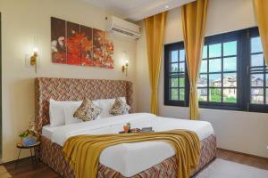a bedroom with a large white bed with yellow curtains at Badakshan Bliss in Srinagar