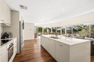 eine offene Küche mit weißen Schränken und ein Wohnzimmer in der Unterkunft Casa Indigo - Modern Bushland Retreat by the Sea in Dunsborough