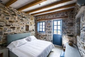 1 dormitorio con cama y pared de piedra en Alika Resort, en Álika