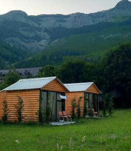 a log cabin in a field with mountains in the background at Boga Cabins in Bogë +23 photos