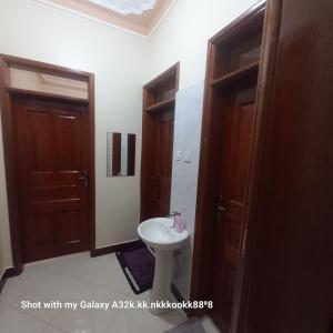 a bathroom with a sink and two wooden doors at Celesta House in Mbarara