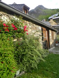 a stone house with red flowers on the side of it at L'Arcouli in Sers