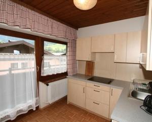 a kitchen with white cabinets and a large window at Haus Elisabeth in Mittersill