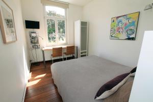 1 dormitorio con cama, escritorio y ventana en Le Home, en Maastricht