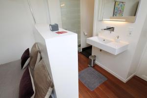 ein weißes Badezimmer mit einem Waschbecken und einem Spiegel in der Unterkunft Le Home in Maastricht