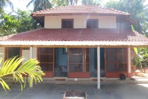 a small house with red doors and a roof at Veeru River Front Nature Homestay Honnavar in Honāvar +5 photos
