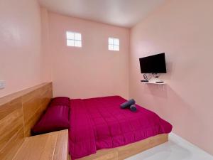 a bedroom with a red bed and a flat screen tv at Moon Village Khaoyai Holiday Home in Pong Talong