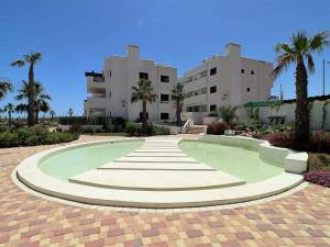 a swimming pool in front of a building with palm trees at Apartamento moderno con piscina, a 500m de la playa, San Juan de los Terreros - ES-376-41 in Pulpí