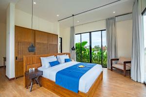 a bedroom with a large bed with a blue blanket at 4BR Rice Fields view & Spa Villa Abian in Sukawati +11 photos