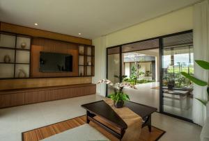 a living room with a table and a tv at 4BR Rice Fields view & Spa Villa Abian in Sukawati