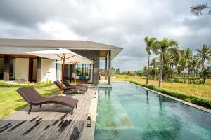 a pool with chairs and an umbrella next to a house at 4BR Rice Fields view & Spa Villa Abian in Sukawati