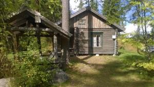 a log cabin in the woods with a tree at Löydön Kartano Camping in Mikkeli