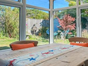 a dining room table with chairs and a large window at Garden Cottage in Pakefield