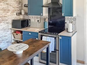 a kitchen with blue cabinets and a wooden table at Garden Cottage in Pakefield +5 photos