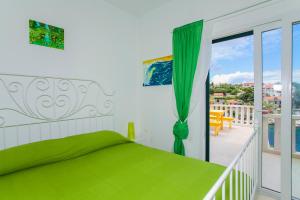 a bedroom with a green bed and a balcony at Villa Lav in Prigradica