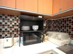 a kitchen with a microwave oven with dishes in it at Urbana Home in Hat Yai