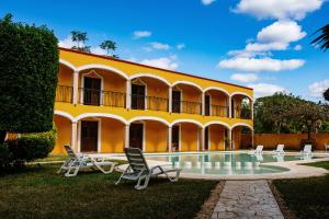a yellow building with chairs and a swimming pool at Hotel Tuul in Izamal