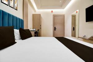 a bedroom with a large white bed and a desk at Super Townhouse Bairhana Road Prayagraj in Colonelganj +23 photos