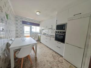 a kitchen with white appliances and a white table and chairs at Panxon, Arquitecto Palacios, piso con terraza in Nigrán