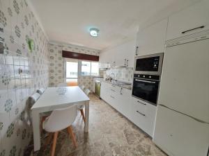 a kitchen with white cabinets and a white table at Panxon, Arquitecto Palacios, piso con terraza in Nigrán +11 photos