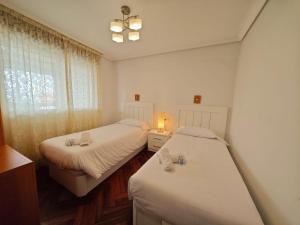 a bedroom with two beds and a window at Panxon, Arquitecto Palacios, piso con terraza in Nigrán