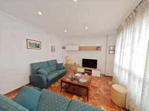 a living room with two blue couches and a tv at Panxon, Arquitecto Palacios, piso con terraza in Nigrán