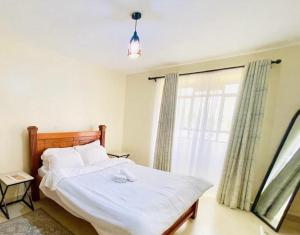 een slaapkamer met een wit bed met een raam bij Sweethaven in Nairobi