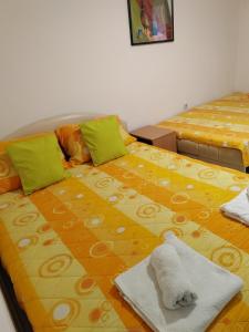 a bedroom with two beds with yellow and orange sheets at Soko S apartmani in Soko Banja
