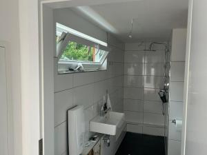 a white bathroom with a sink and a window at Naturhaus am Weiher in Hülsen