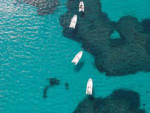 three boats in the water next to a island at Sa Tirìa in Chia