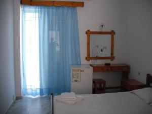 a bedroom with a refrigerator and a window with blue curtains at Antonis Hotel in Kefalos