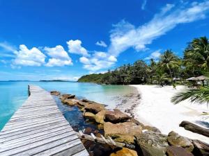 a wooden pathway leading to a beach with palm trees at Baan Nara Homestay - Koh Kood in Ko Kood