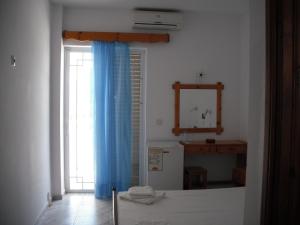 a bedroom with a blue curtain and a window at Antonis Hotel in Kefalos