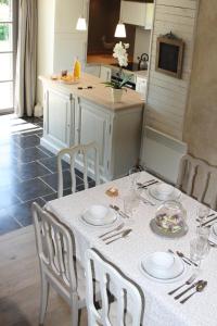 eine Küche mit einem Tisch mit weißen Tellern und Stühlen in der Unterkunft A l´Ombre Du Clocher in Montbliart