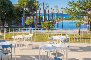 un grupo de mesas y sillas con el océano en el fondo en Amadria Park Beach Hotel Jure, en Šibenik