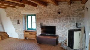a living room with a tv and a stone wall at Holiday home Olea in Malinska