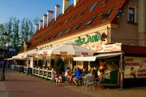 grupa ludzi siedzących pod parasolami przed restauracją w obiekcie Apartamenty Sielawa w mieście Mikołajki