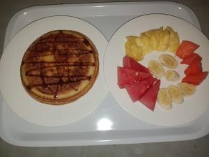 a plate of food with a waffle and fruit on it at Teman Homestay in Kuta Lombok +12 photos