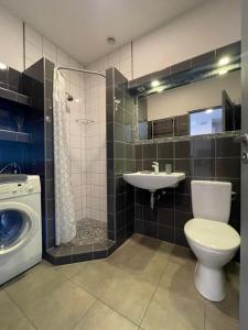 a bathroom with a toilet and a sink and a washing machine at newTown City Center Apartment Kaunas in Kaunas +3 photos