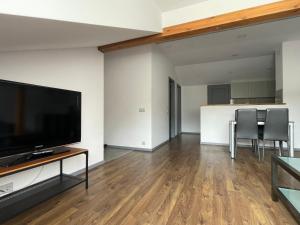 a living room with a flat screen tv and a table with chairs at newTown City Center Apartment Kaunas in Kaunas