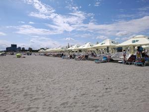a group of people sitting on a beach with umbrellas at Kogaion Place in Douăzeci şi Trei August
